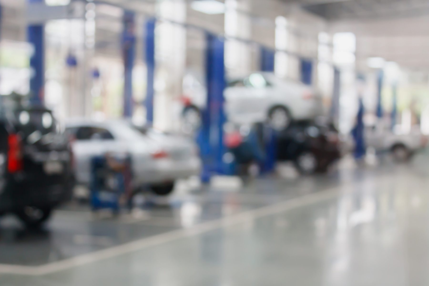 A busy collision repair shop floor, vehicles up on lifts across the bay